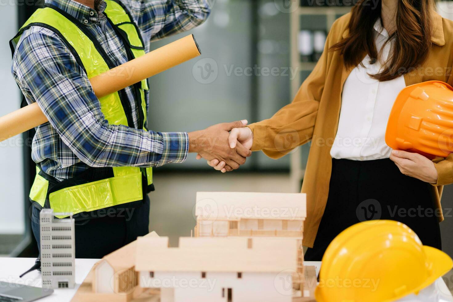 Two colleagues discussing data working and tablet, laptop with on architectural project at construction site at desk in modern office photo