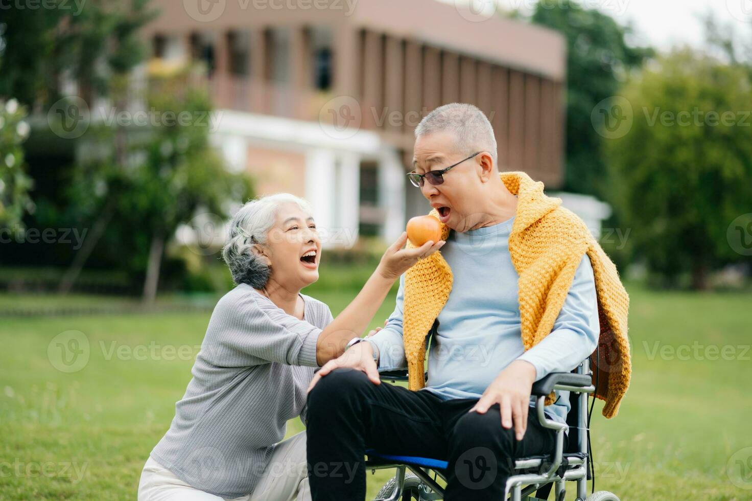 Asian Senior couple sitting in wheelchairs taking care of each other.in romantic time They laughing and smiling while sitting outdoor in park. photo