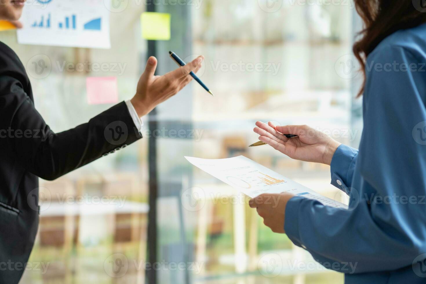 A man employee writes on a colorful notepad. Ethnic women working at startups brainstorm collaborative plans on glass wall stickers See less. photo