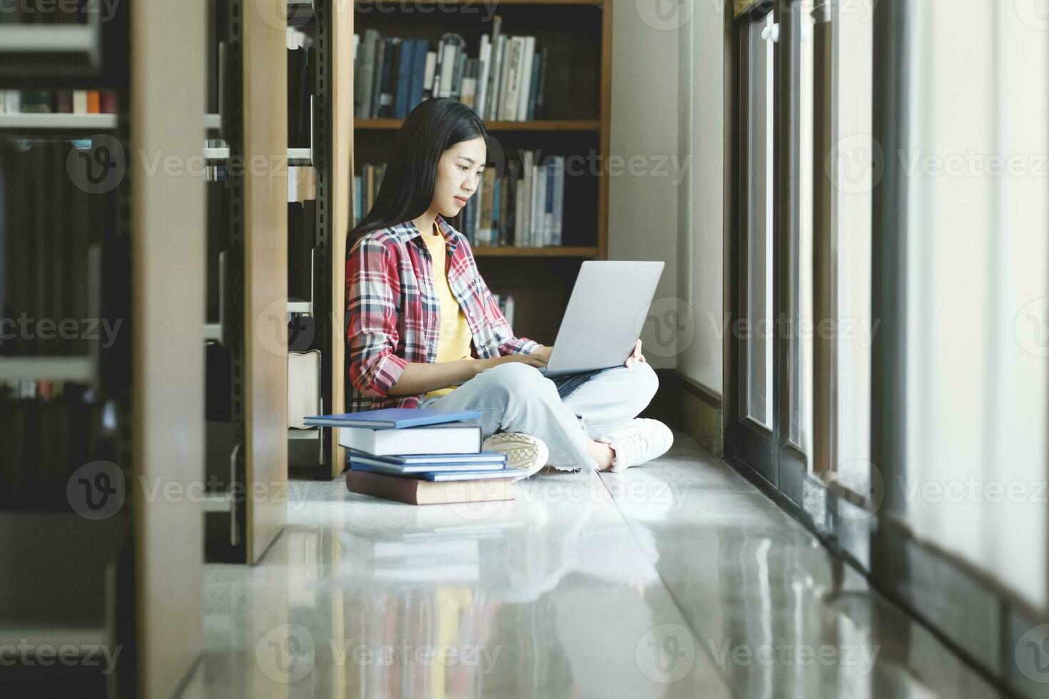 Young university student using laptop for online learning, searching and learning at library. photo