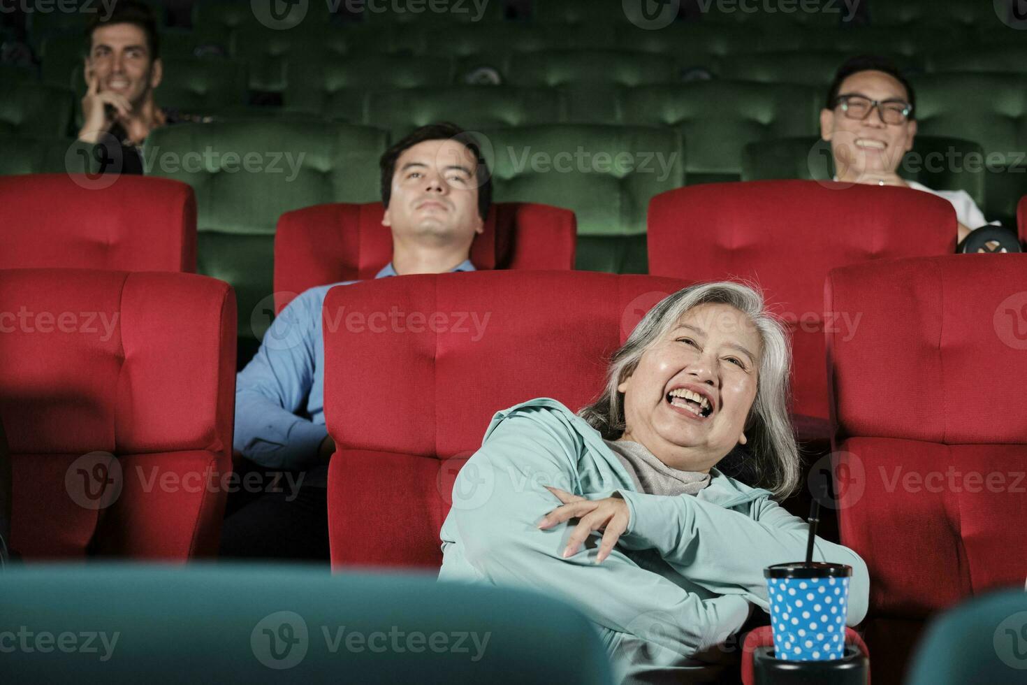 Various people enjoy watching comedy cinema in movie theaters. Senior Asian woman and audiences have a fun indoor entertainment lifestyle with film art shows, happy and cheerful with drink and smiles. photo