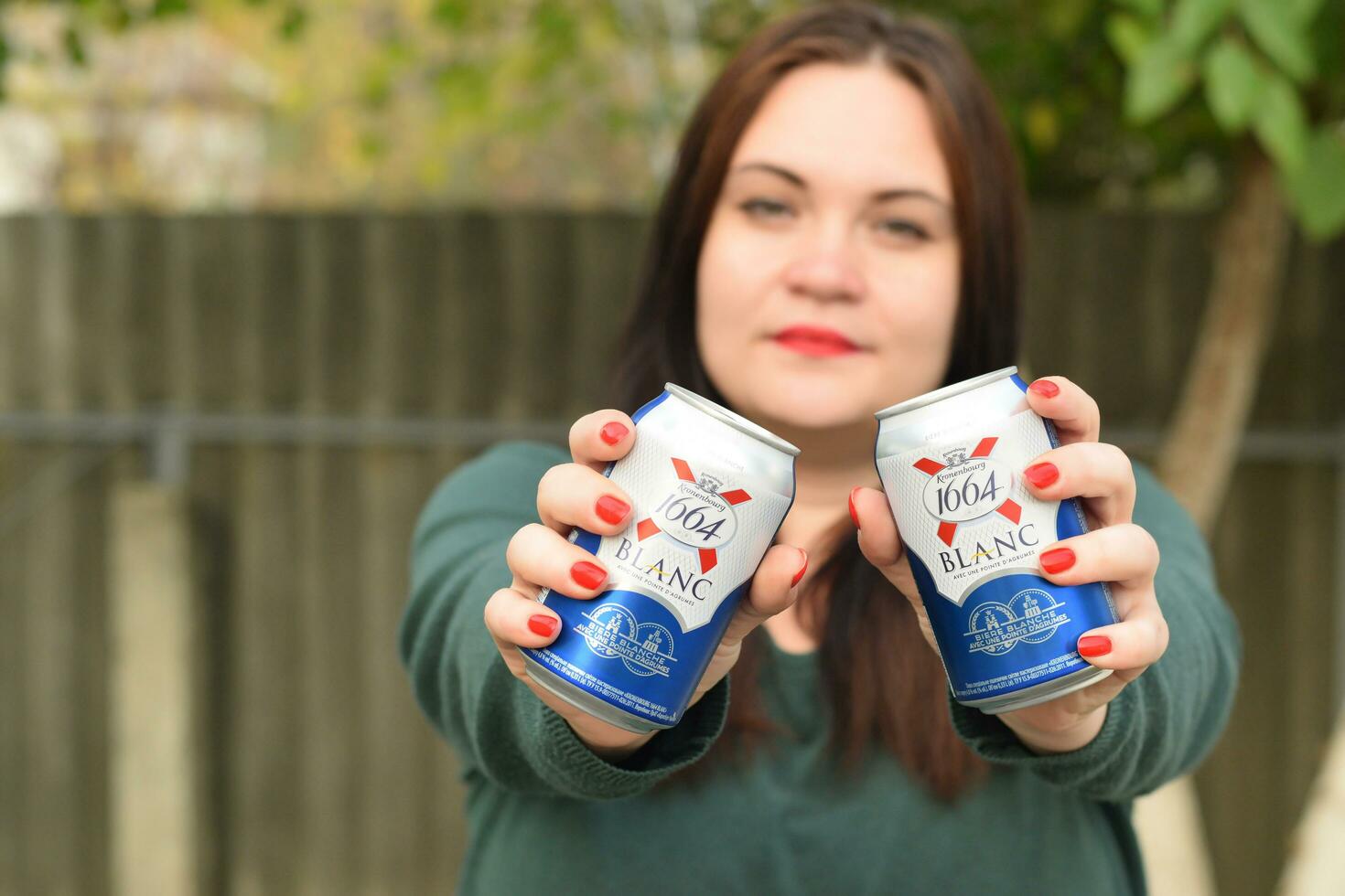Young girl holds 1664 Kronenbourg Blanc beer can outdoors. 1664 Blanc is the wheat beer from the French brewery Kronenbourg exported worldwide photo