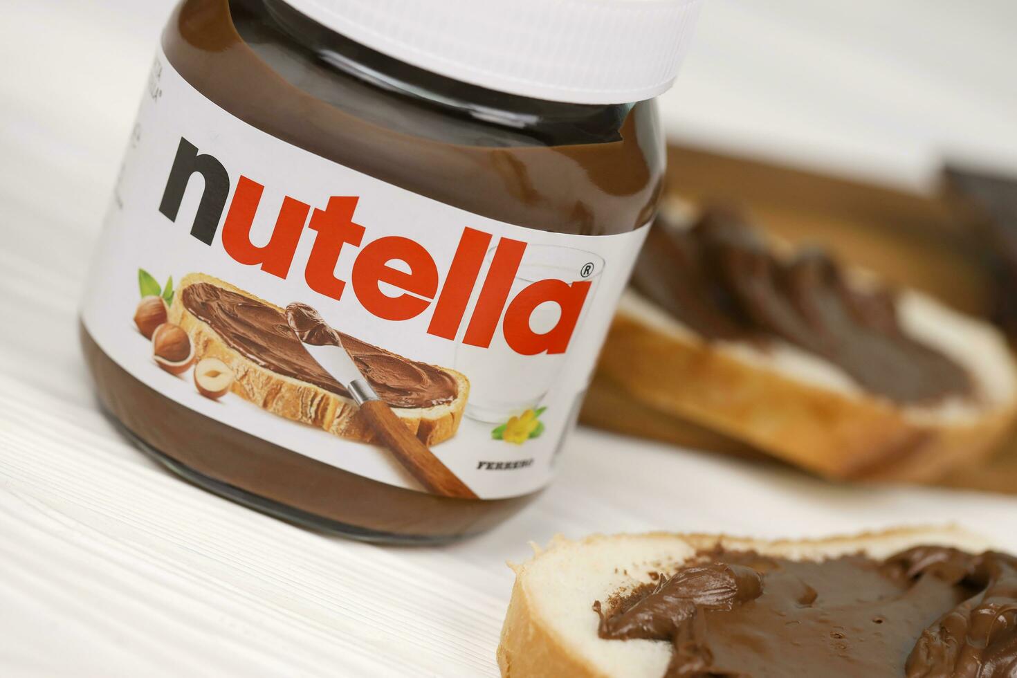 KHARKOV, UKRAINE - DECEMBER 27, 2020 Nutella glass can and spread on freshly baked bread. Nutella is manufactured by Italian company Ferrero first introduced in 1964 photo