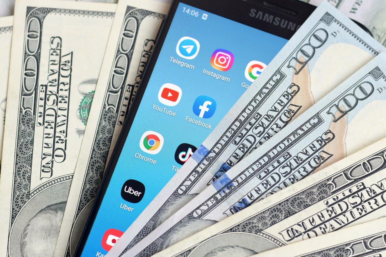 Smartphone screen with many popular apps and lot of hundred dollar bills. Business and social networking concept photo