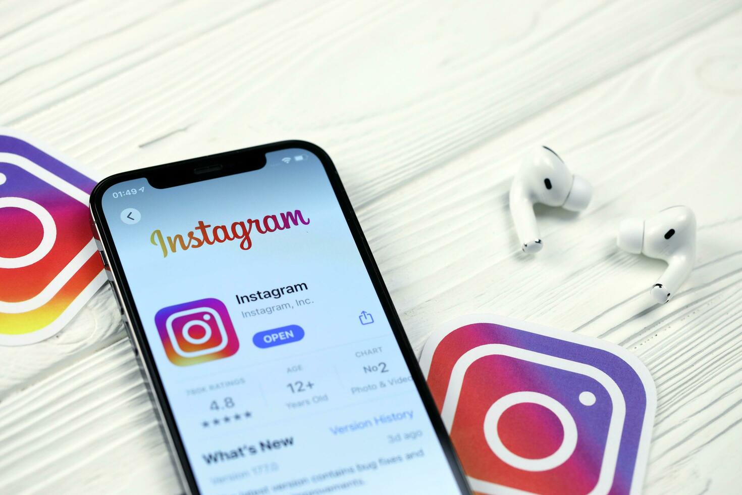 KHARKOV, UKRAINE - MARCH 5, 2021 Instagram icon and application from App store on iPhone 12 pro display screen with airpods pro on white table photo