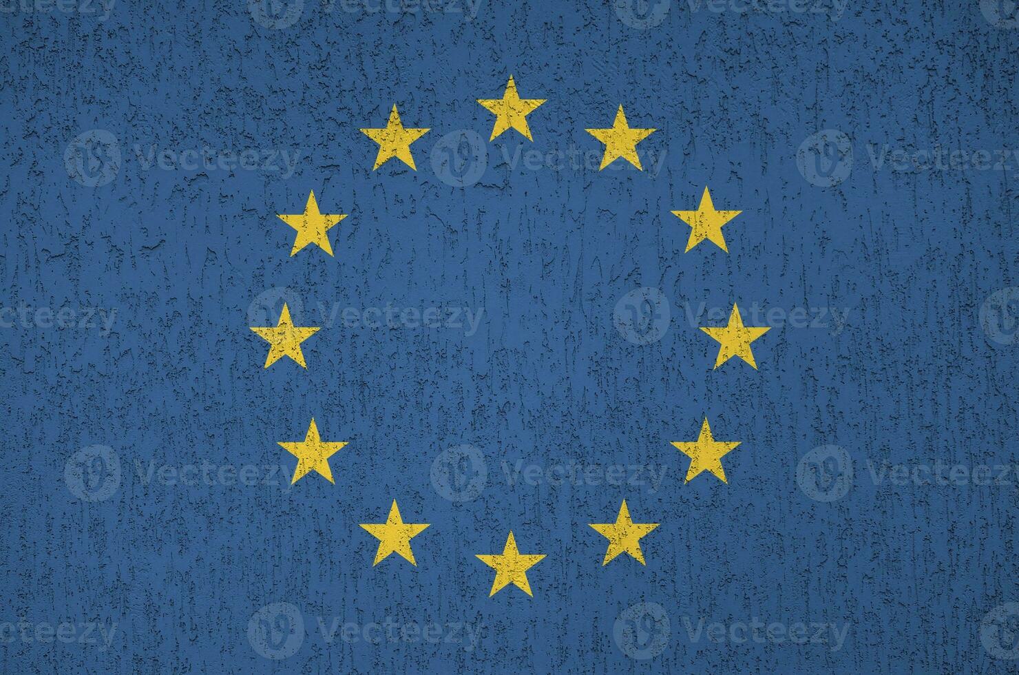 European union flag depicted in bright paint colors on old relief plastering wall. Textured banner on rough background photo