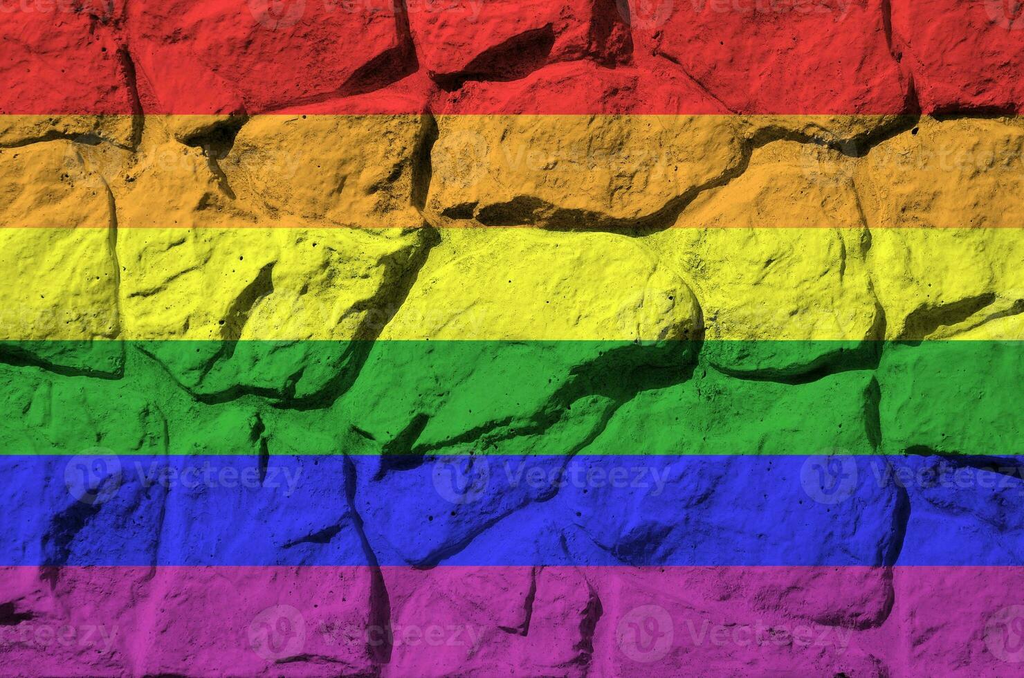 LGBT community flag depicted in paint colors on old stone wall closeup. Textured banner on rock wall background photo
