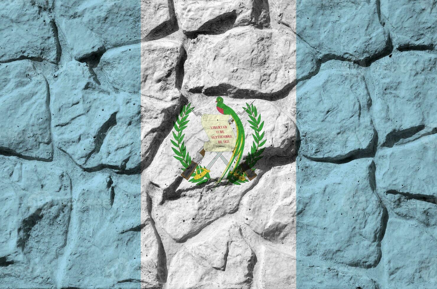 Guatemala flag depicted in paint colors on old stone wall closeup. Textured banner on rock wall background photo