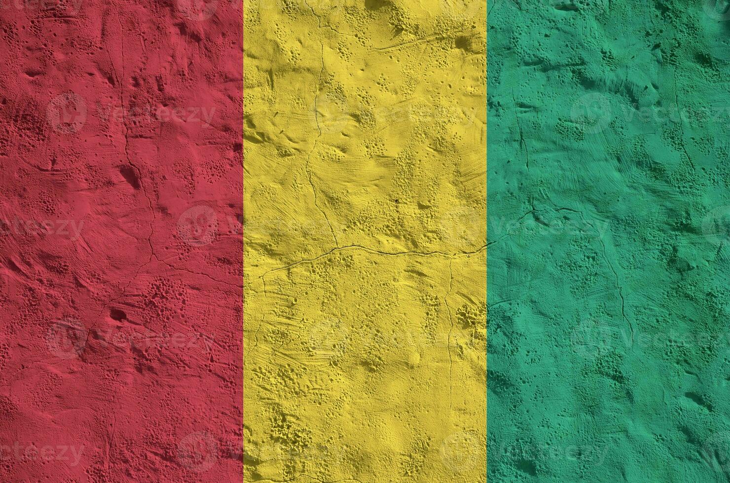Guinea flag depicted in bright paint colors on old relief plastering wall. Textured banner on rough background photo