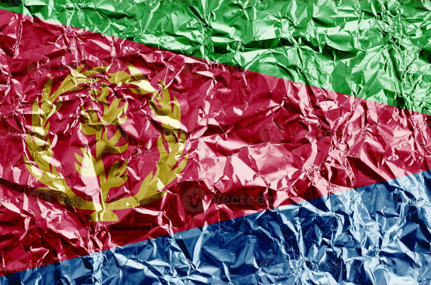 Eritrea flag depicted in paint colors on shiny crumpled aluminium foil closeup. Textured banner on rough background photo