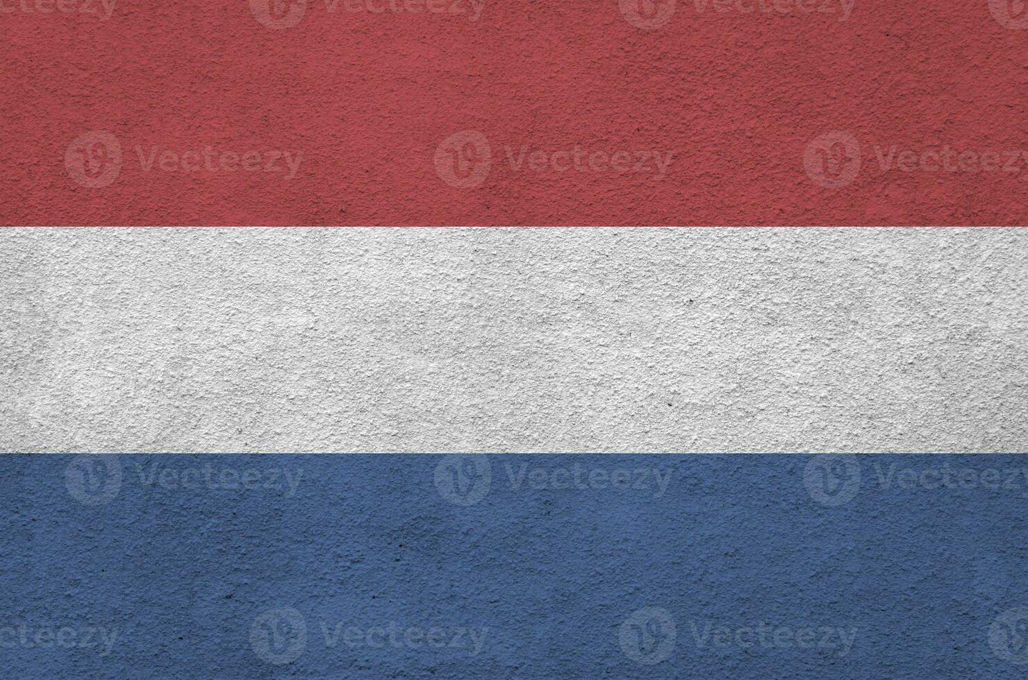 Netherlands flag depicted in bright paint colors on old relief plastering wall. Textured banner on rough background photo