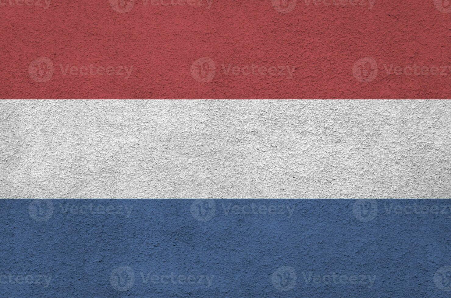 Netherlands flag depicted in bright paint colors on old relief plastering wall. Textured banner on rough background photo