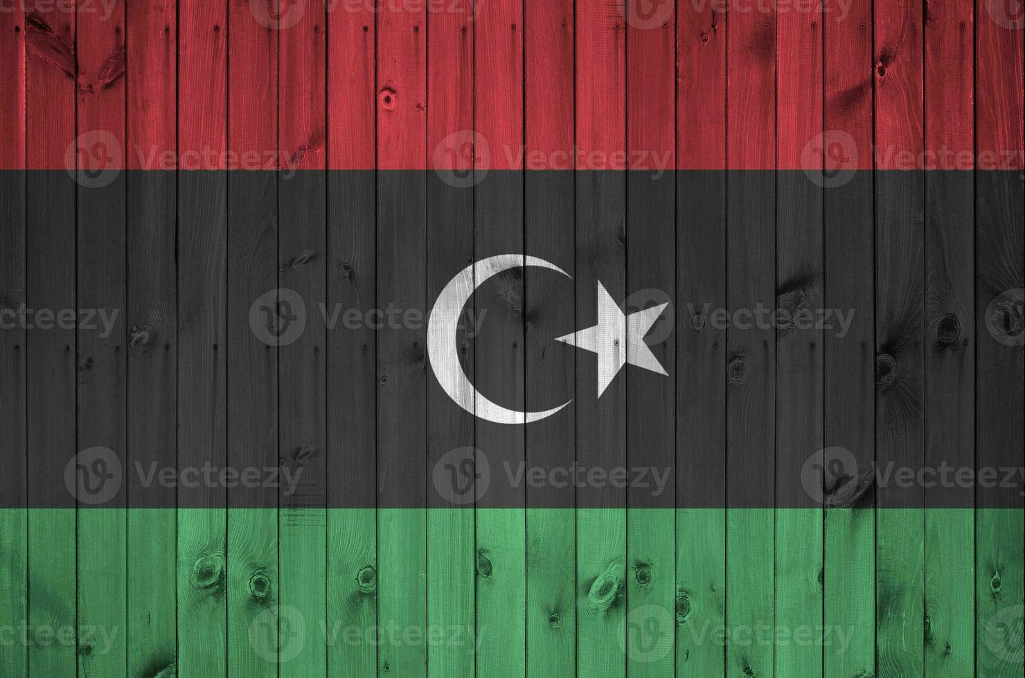 Libya flag depicted in bright paint colors on old wooden wall. Textured banner on rough background photo