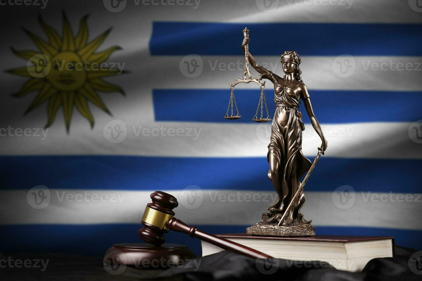 Uruguay flag with statue of lady justice, constitution and judge hammer on black drapery. Concept of judgement and guilt photo
