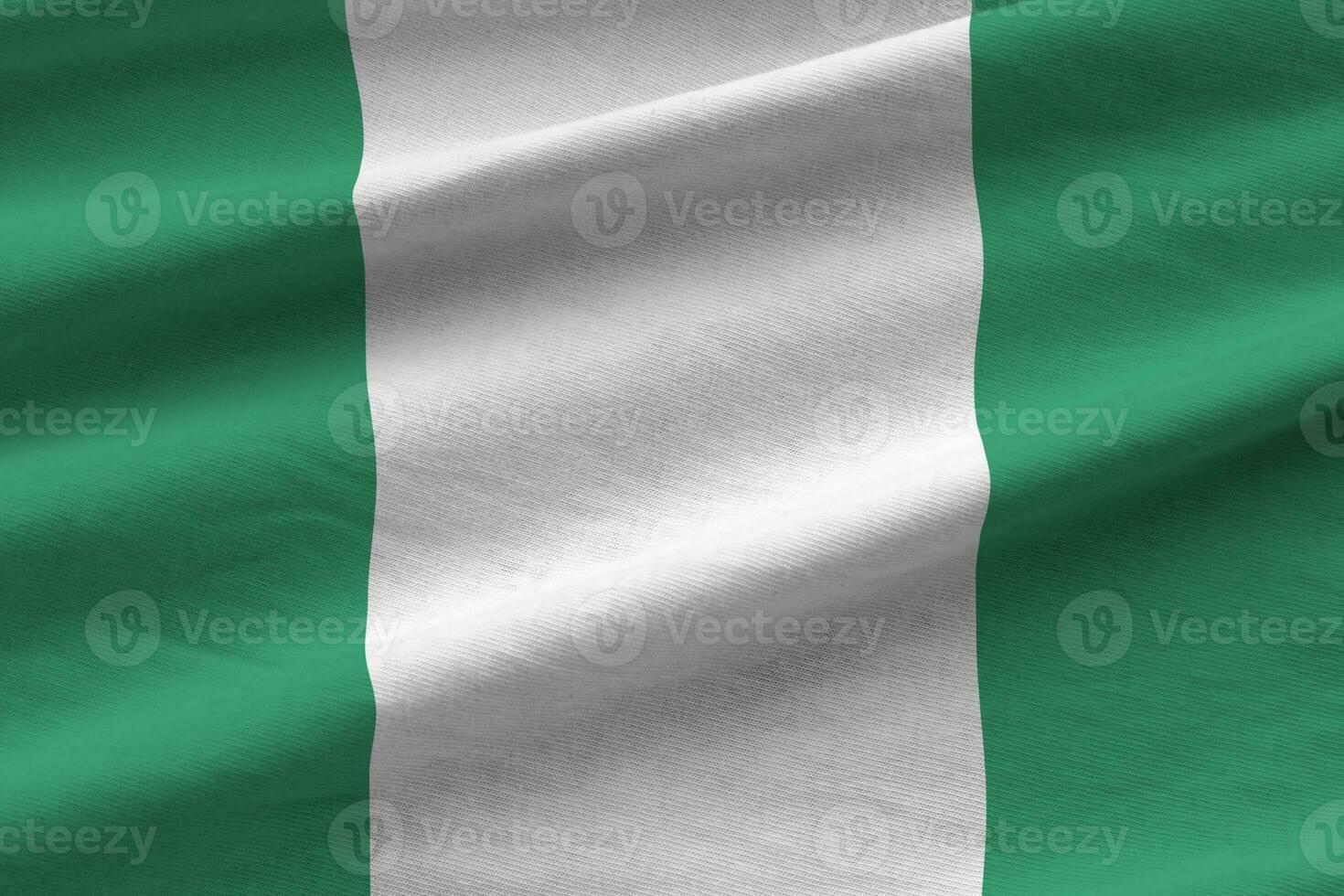 Nigeria flag with big folds waving close up under the studio light indoors. The official symbols and colors in banner photo