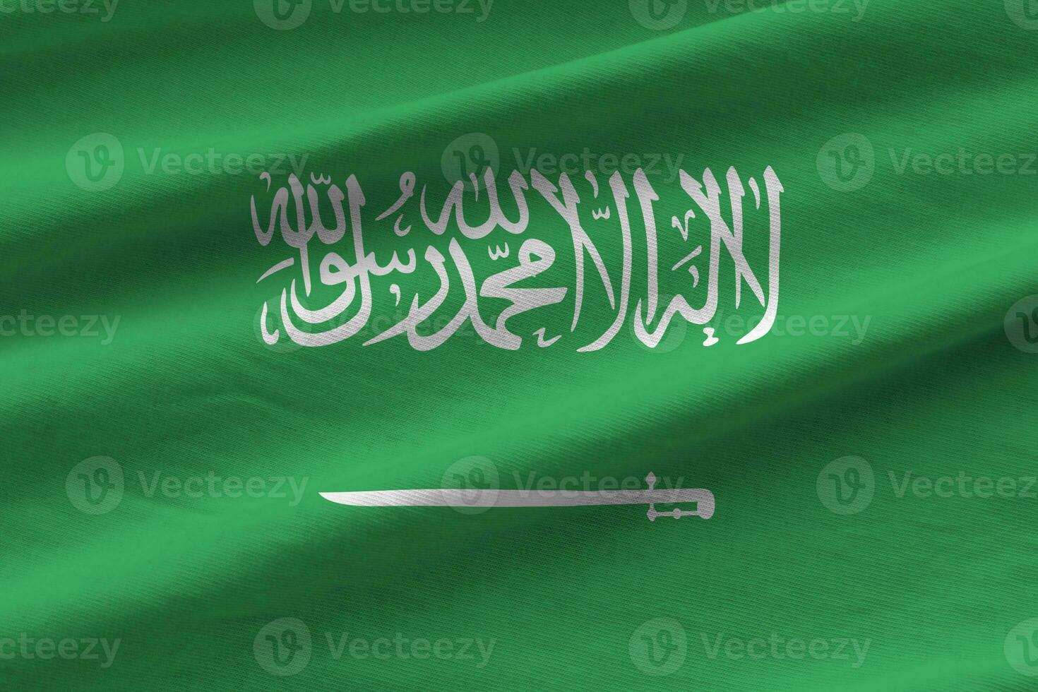 Saudi Arabia flag with big folds waving close up under the studio light indoors. The official symbols and colors in banner photo