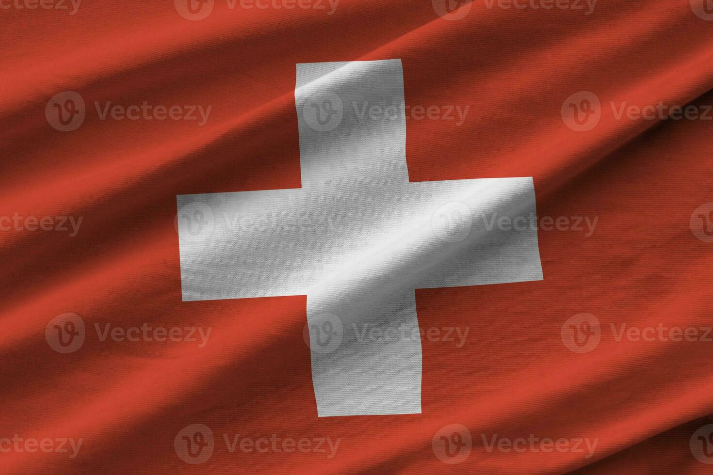 bandera suiza con grandes pliegues ondeando de cerca bajo la luz del estudio en el interior. los símbolos y colores oficiales en banner foto