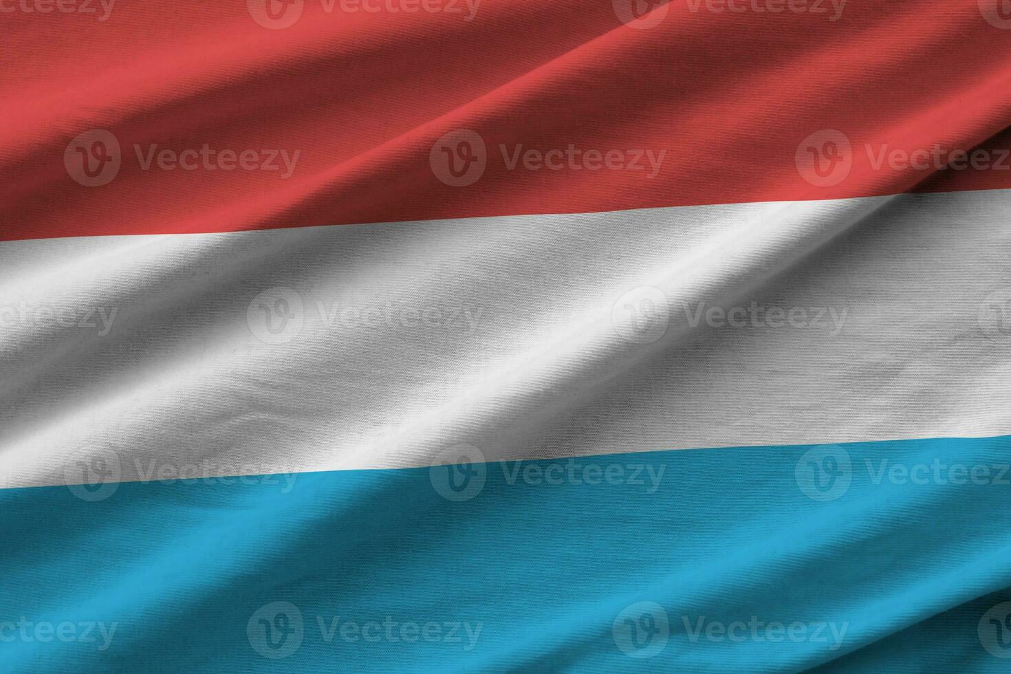 Luxembourg flag with big folds waving close up under the studio light indoors. The official symbols and colors in banner photo