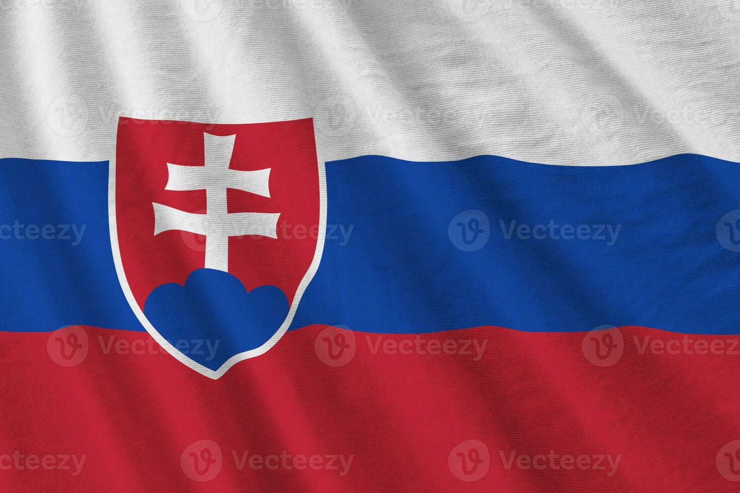 Slovakia flag with big folds waving close up under the studio light indoors. The official symbols and colors in banner photo