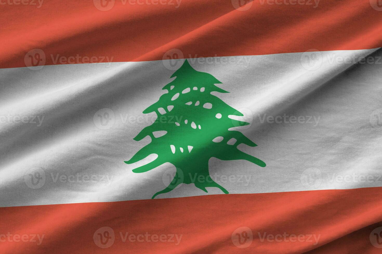 Lebanon flag with big folds waving close up under the studio light indoors. The official symbols and colors in banner photo