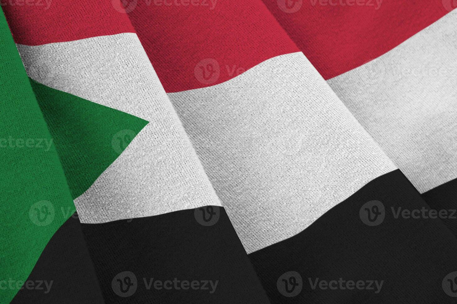 bandera de sudán con grandes pliegues ondeando de cerca bajo la luz del estudio en el interior. los símbolos y colores oficiales en banner foto