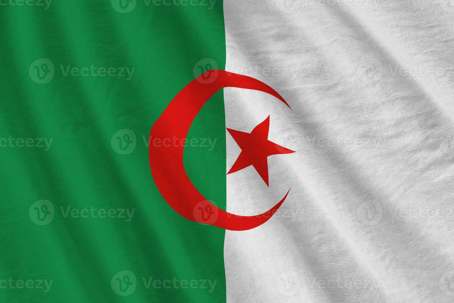 Algeria flag with big folds waving close up under the studio light indoors. The official symbols and colors in banner photo