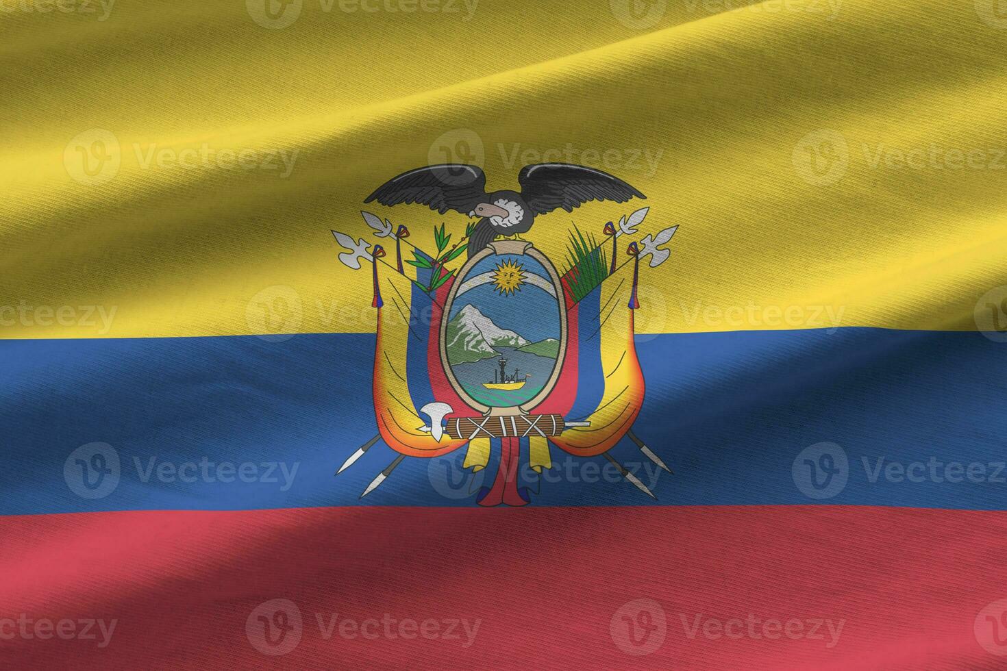 Ecuador flag with big folds waving close up under the studio light indoors. The official symbols and colors in banner photo