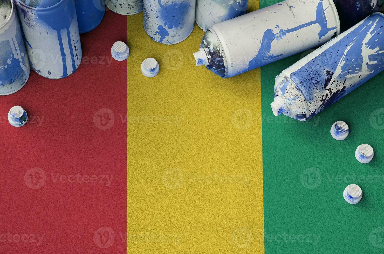 Guinea flag and few used aerosol spray cans for graffiti painting. Street art culture concept photo