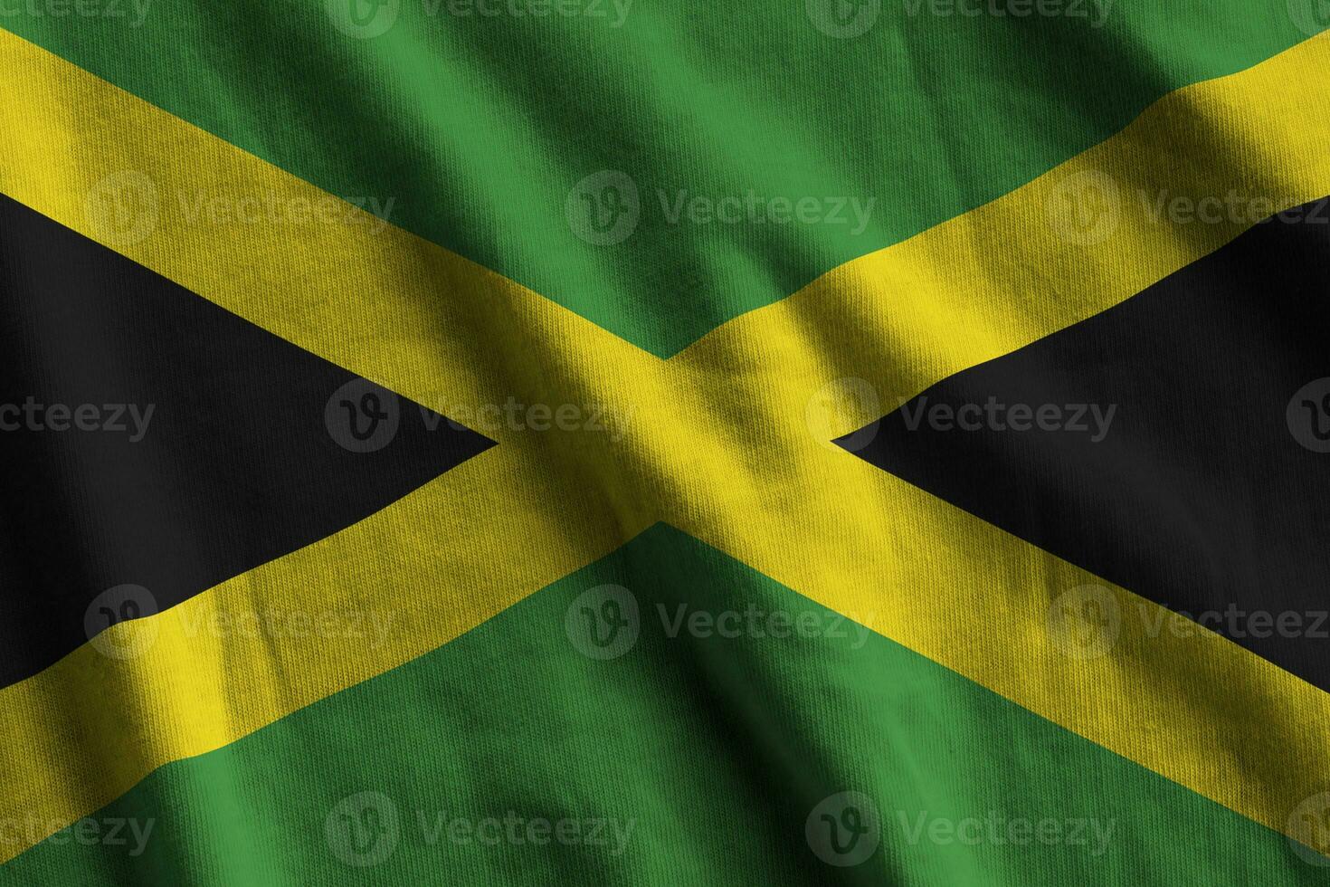 Jamaica flag with big folds waving close up under the studio light indoors. The official symbols and colors in banner photo