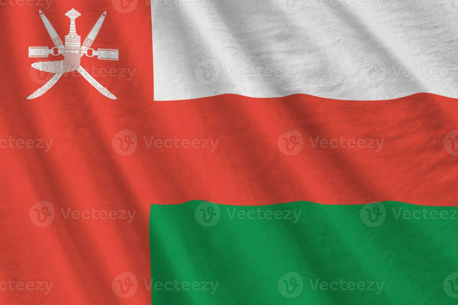 Oman flag with big folds waving close up under the studio light indoors. The official symbols and colors in banner photo