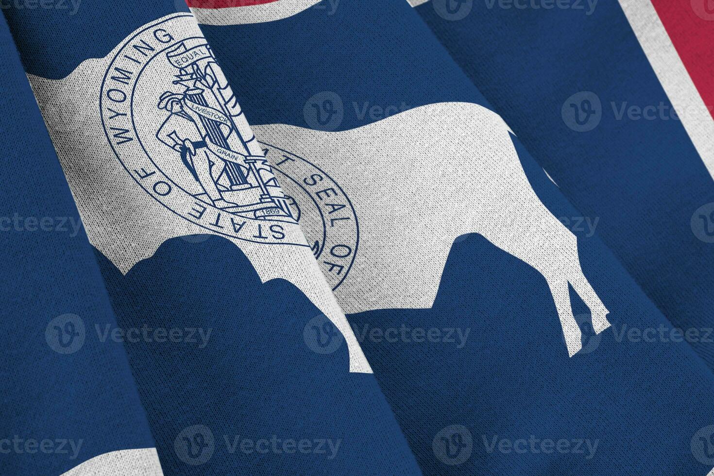 Wyoming US state flag with big folds waving close up under the studio light indoors. The official symbols and colors in banner photo