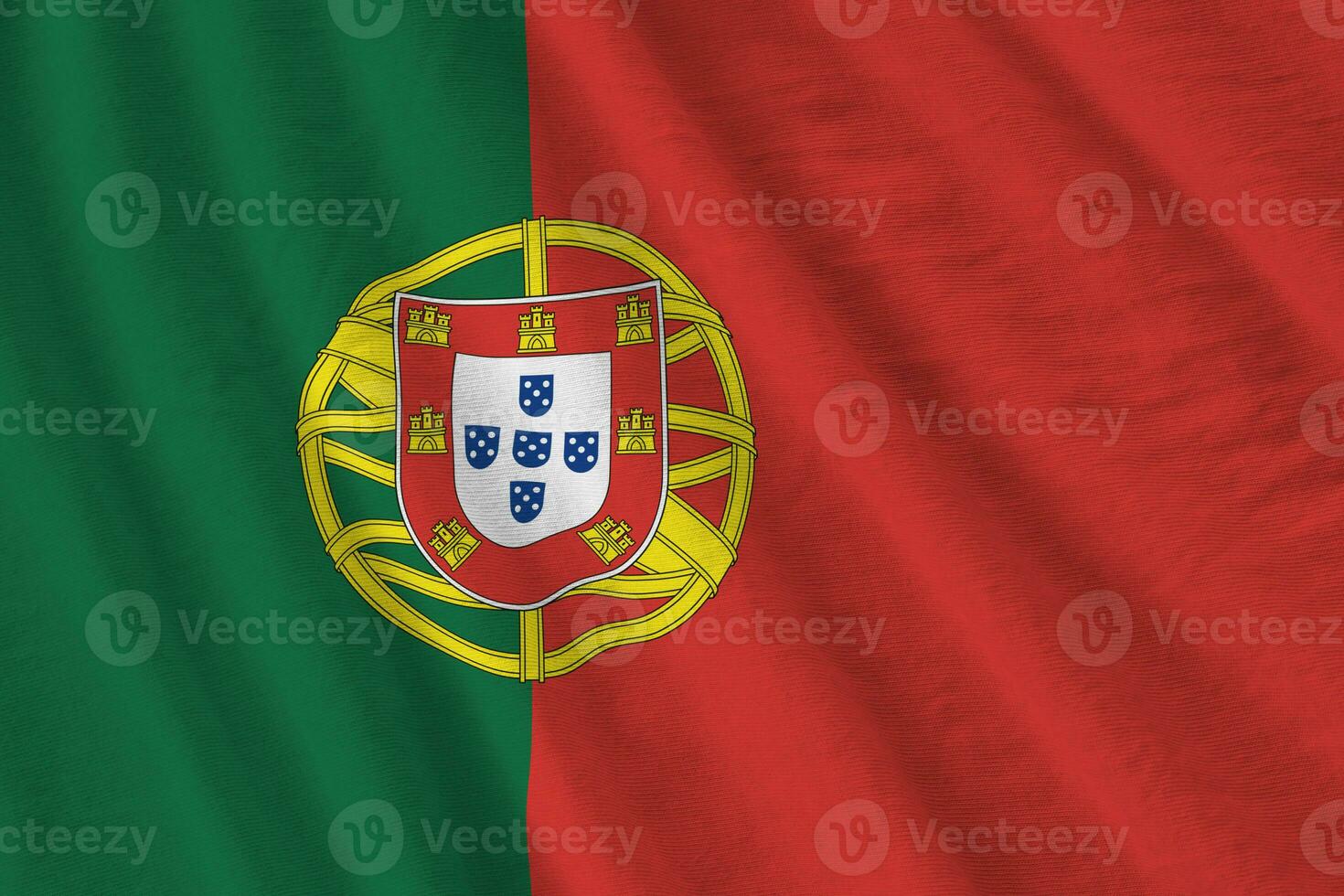 Portugal flag with big folds waving close up under the studio light indoors. The official symbols and colors in banner photo