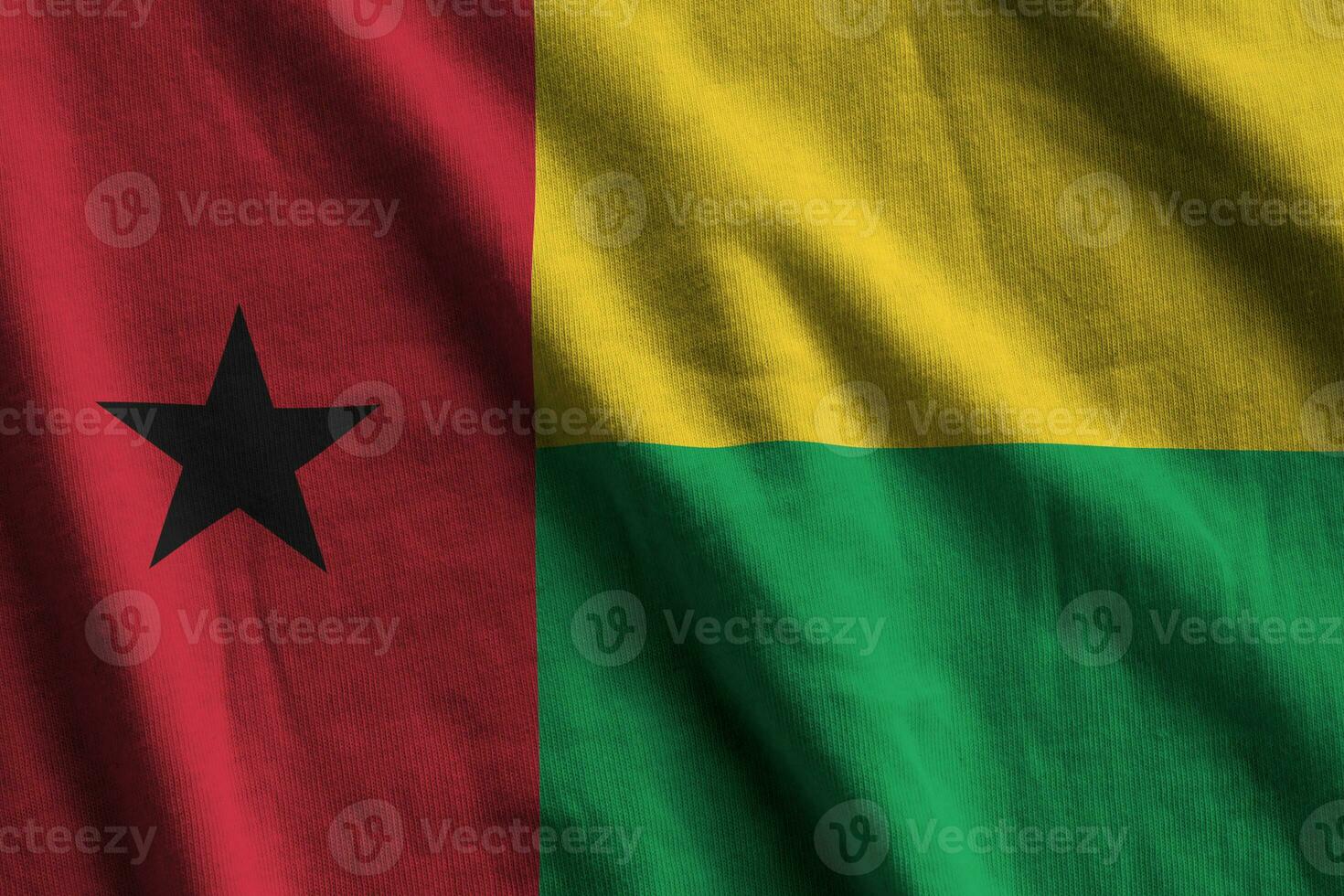 Guinea Bissau flag with big folds waving close up under the studio light indoors. The official symbols and colors in banner photo