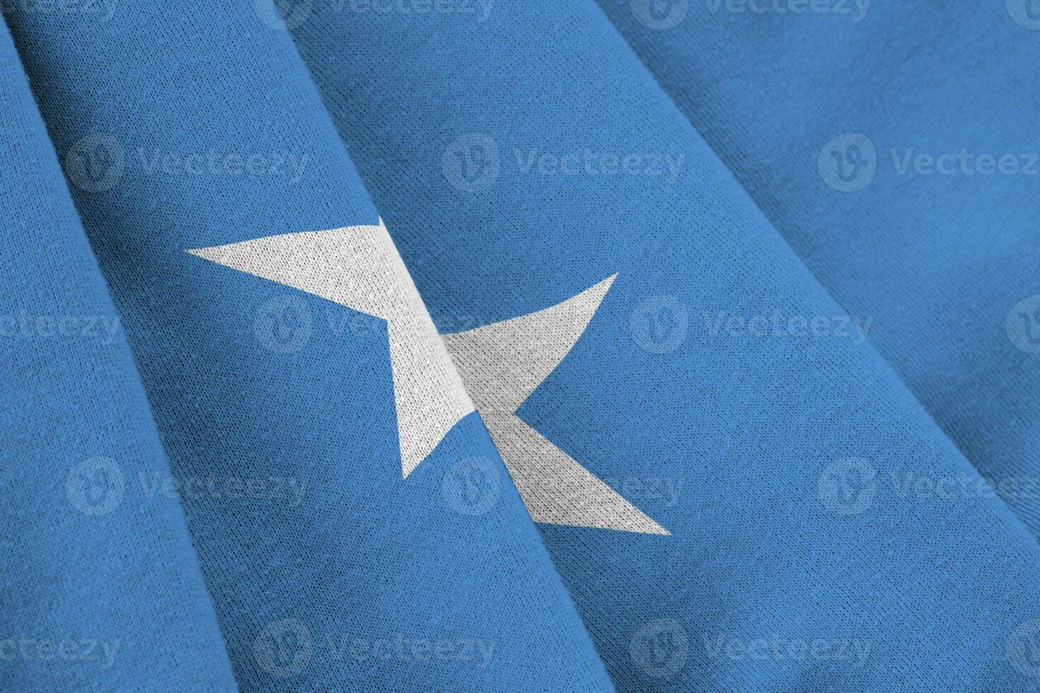 Somalia flag with big folds waving close up under the studio light indoors. The official symbols and colors in banner photo