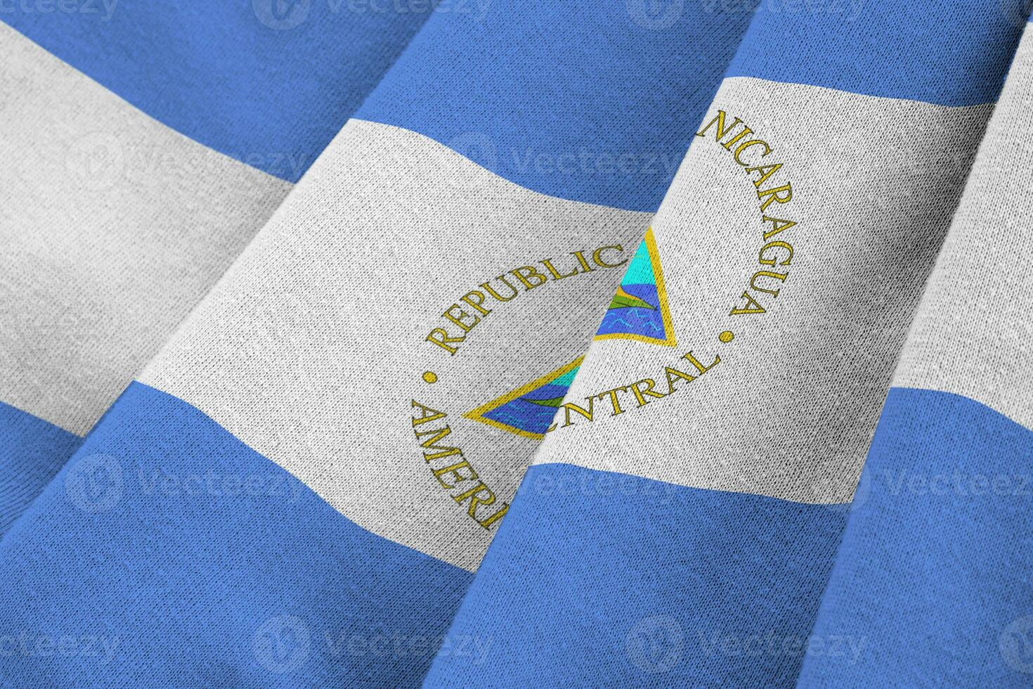 bandera de nicaragua con grandes pliegues ondeando de cerca bajo la luz del estudio en el interior. los símbolos y colores oficiales en banner foto