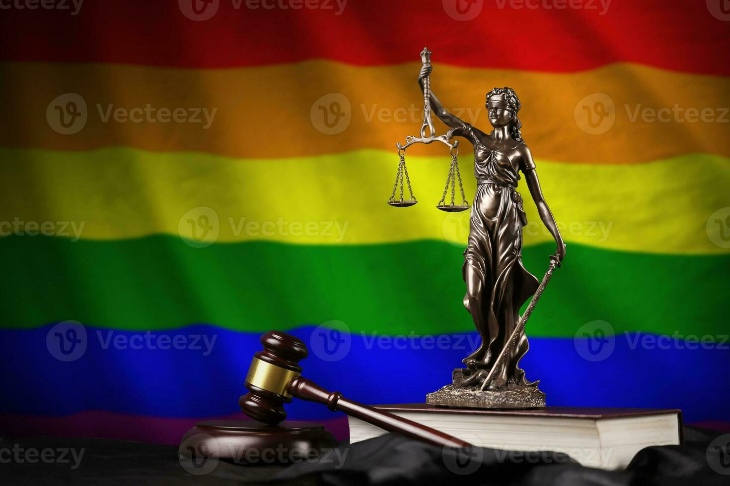 LGBT community flag with statue of lady justice, constitution and judge hammer on black drapery. Concept of judgement and guilt photo