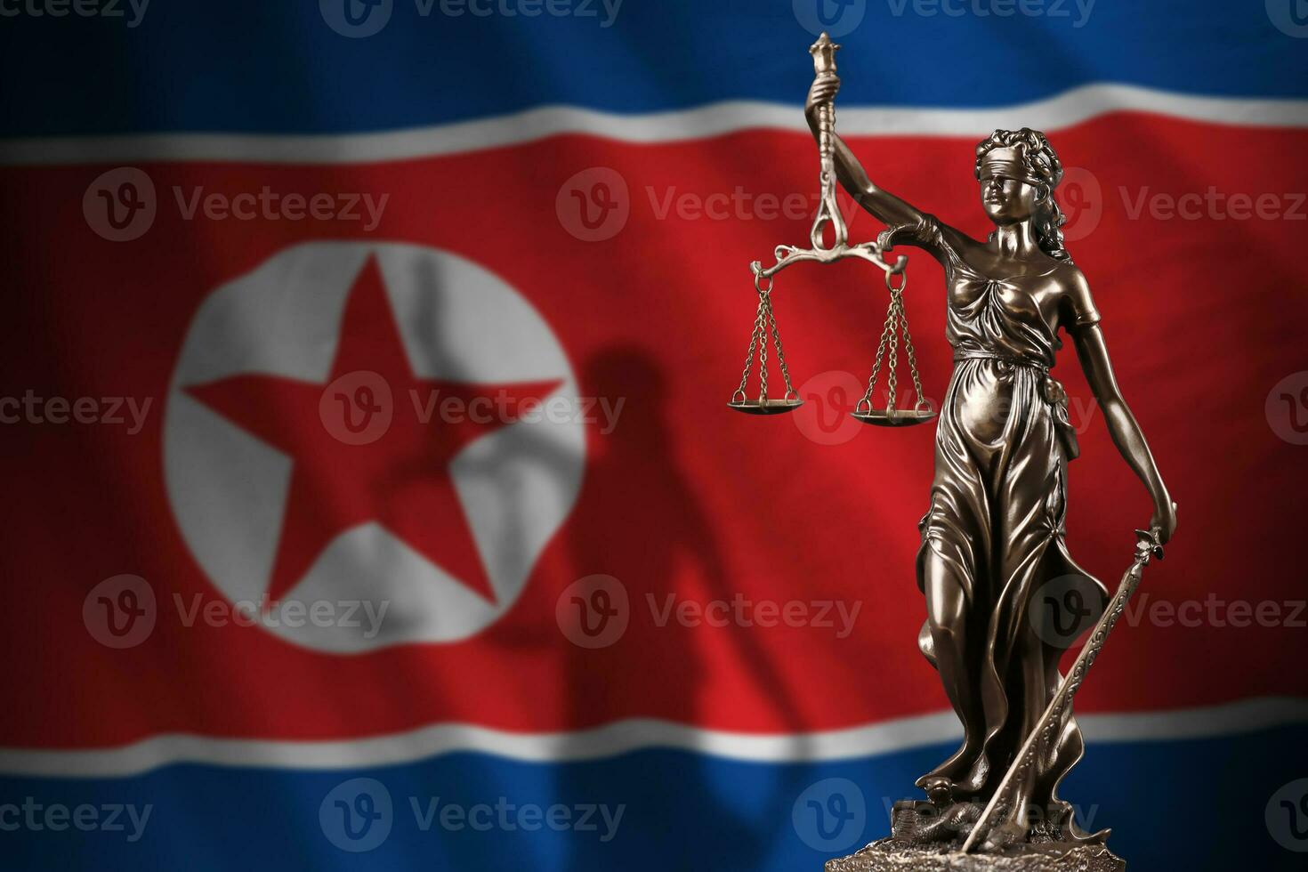 North Korea flag with statue of lady justice and judicial scales in dark room. Concept of judgement and punishment photo