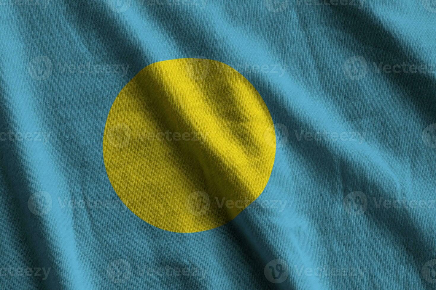 Palau flag with big folds waving close up under the studio light indoors. The official symbols and colors in banner photo