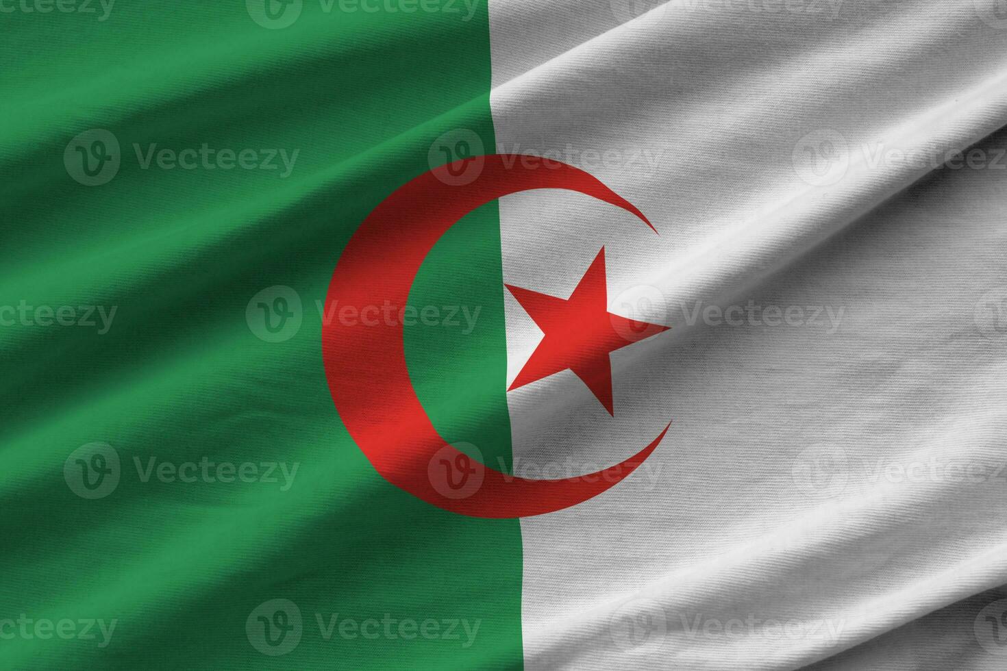 Algeria flag with big folds waving close up under the studio light indoors. The official symbols and colors in banner photo