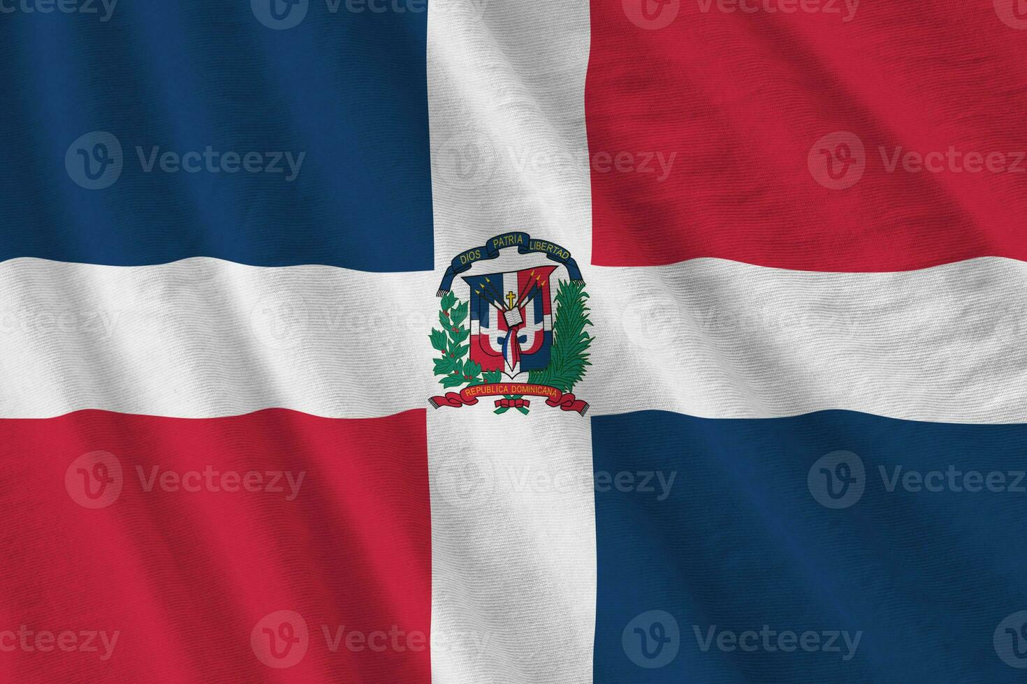 Dominican Republic flag with big folds waving close up under the studio light indoors. The official symbols and colors in banner photo