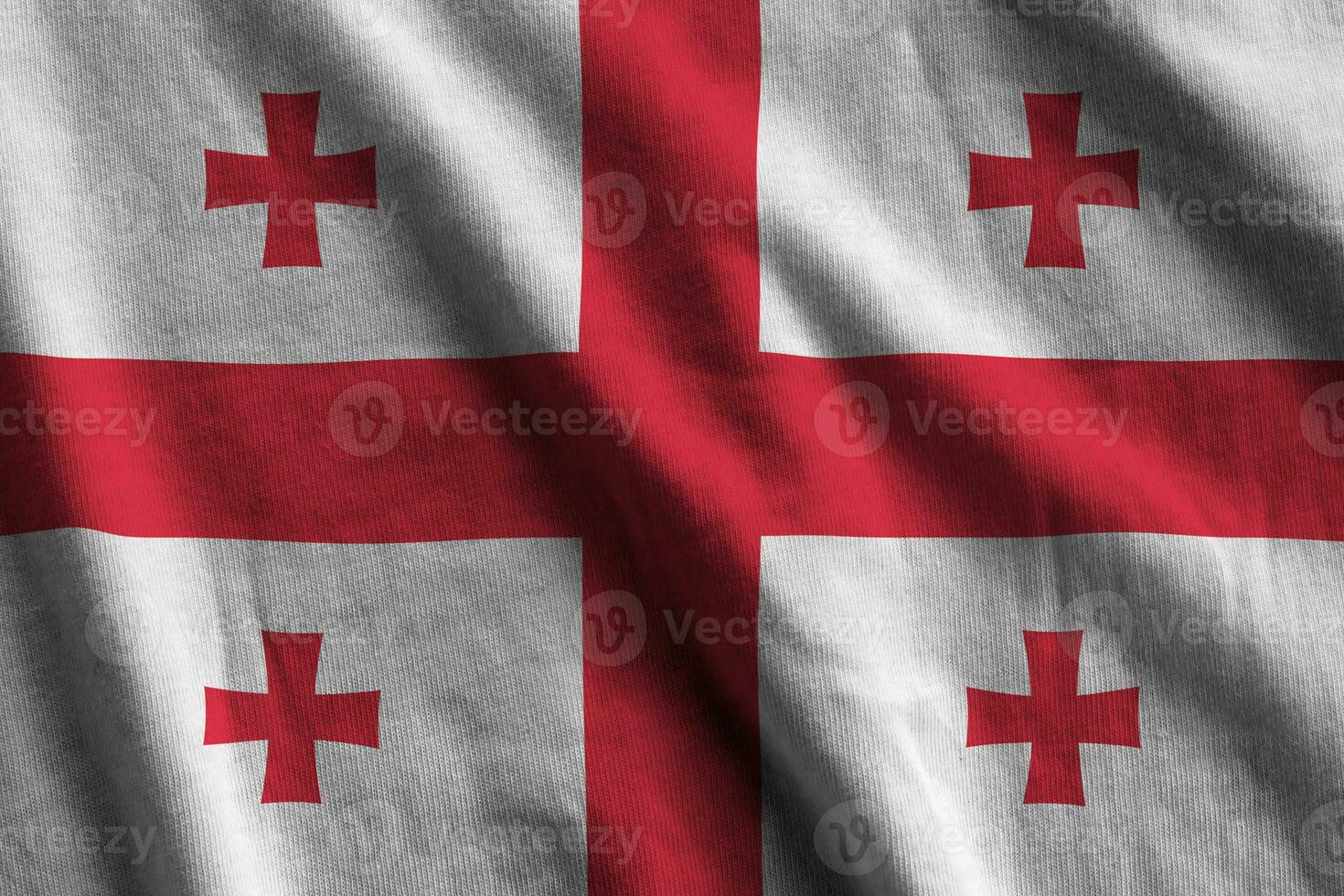 Georgia flag with big folds waving close up under the studio light indoors. The official symbols and colors in banner photo