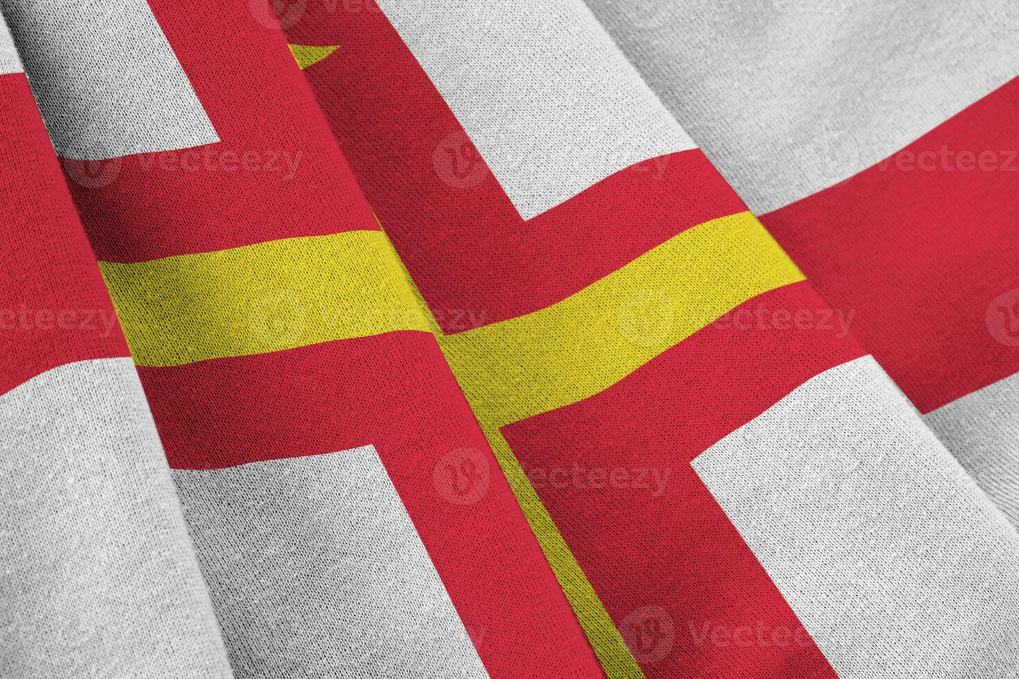 Guernsey flag with big folds waving close up under the studio light indoors. The official symbols and colors in banner photo