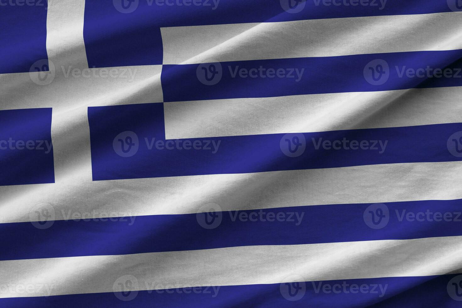 Greece flag with big folds waving close up under the studio light indoors. The official symbols and colors in banner photo
