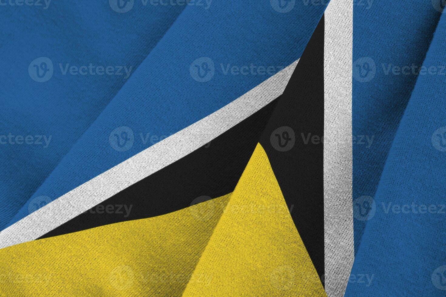 Saint Lucia flag with big folds waving close up under the studio light indoors. The official symbols and colors in banner photo