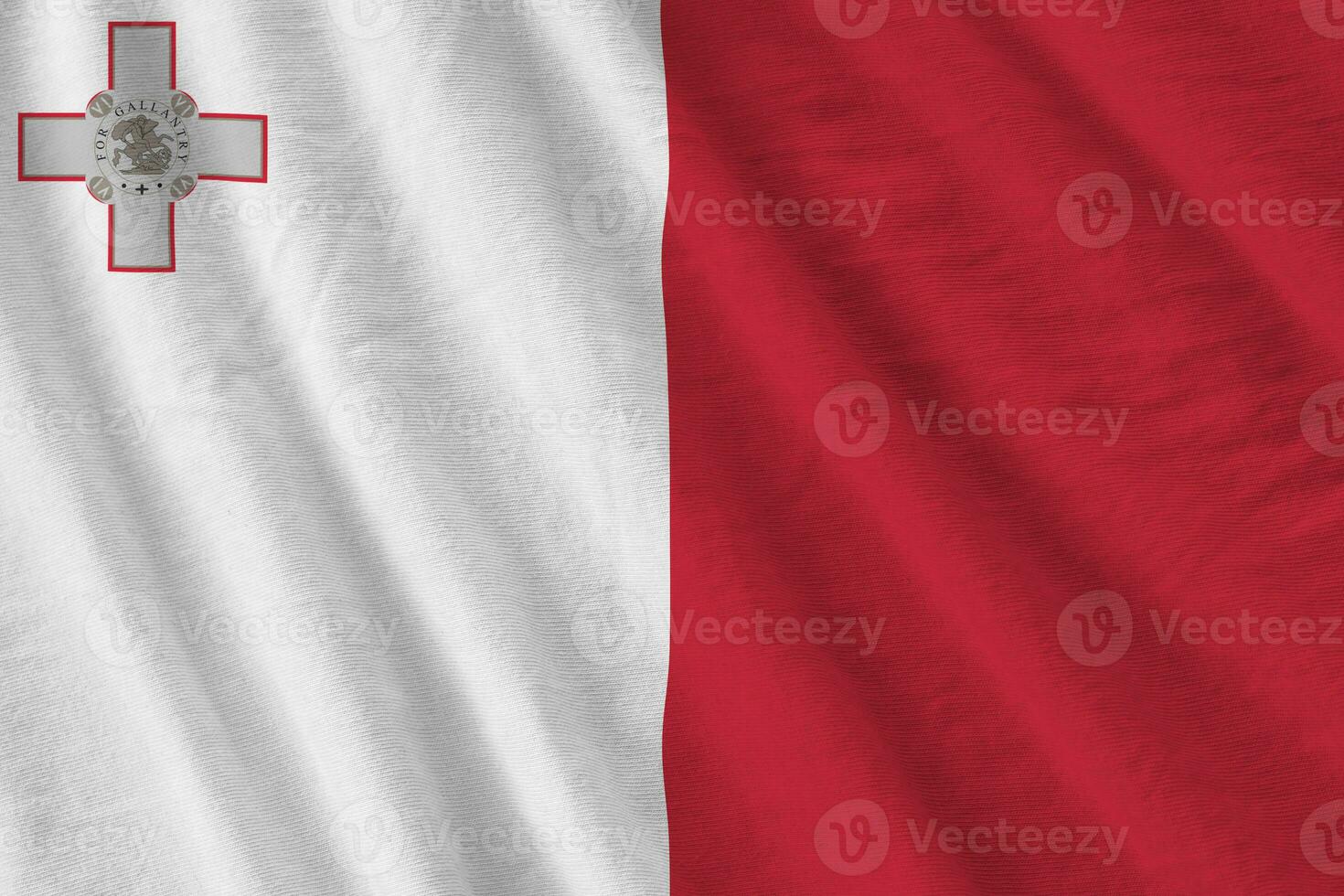 Malta flag with big folds waving close up under the studio light indoors. The official symbols and colors in banner photo