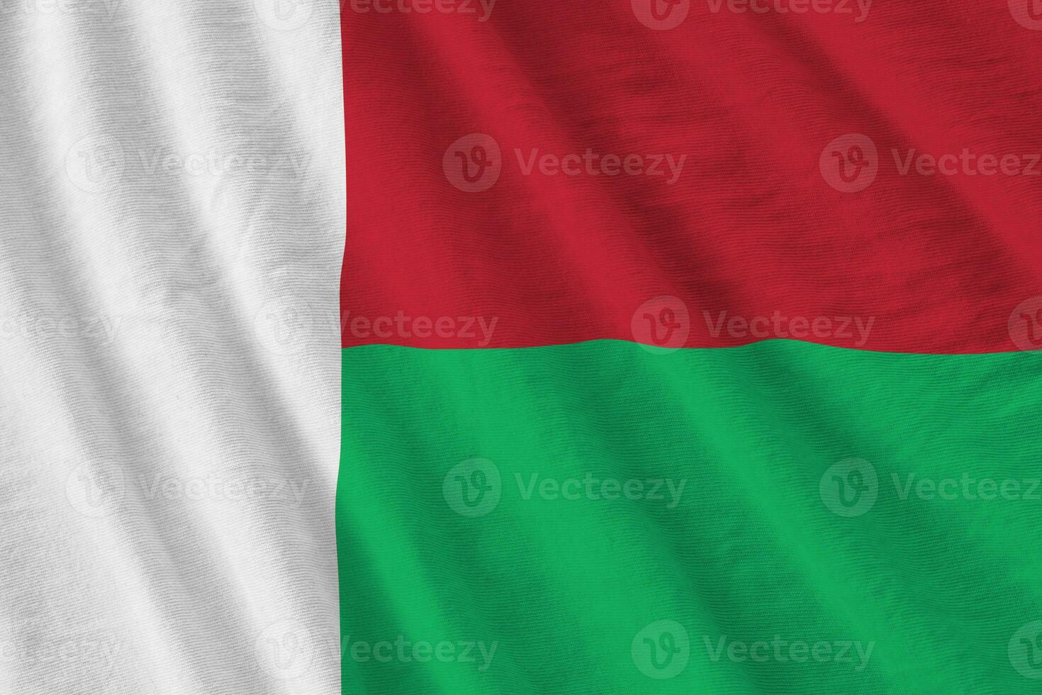 Madagascar flag with big folds waving close up under the studio light indoors. The official symbols and colors in banner photo