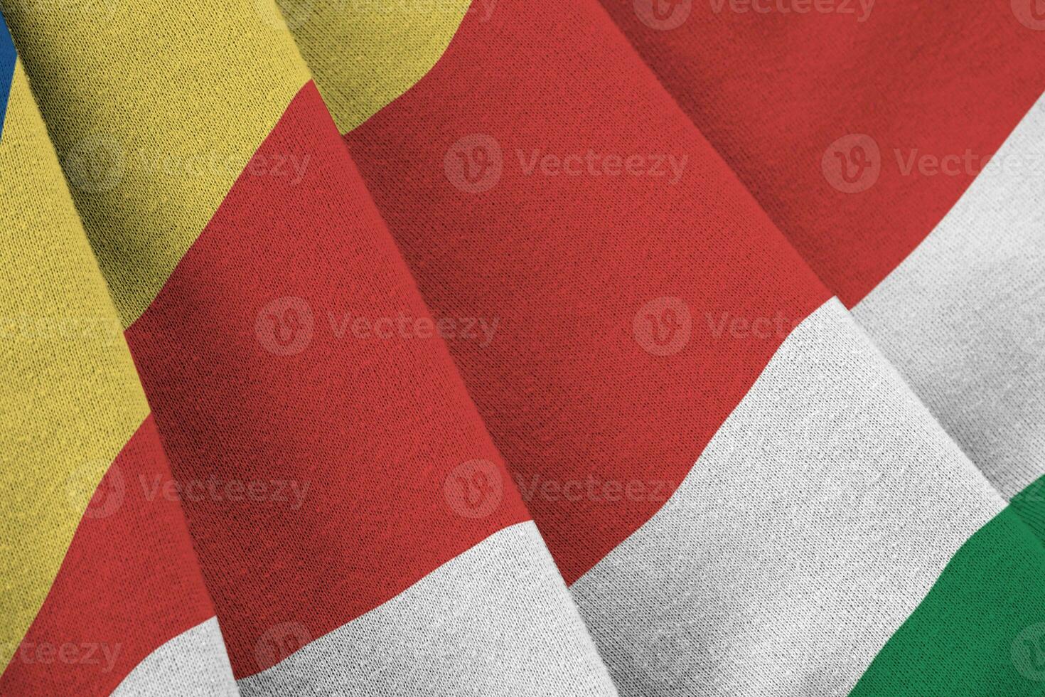 Seychelles flag with big folds waving close up under the studio light indoors. The official symbols and colors in banner photo