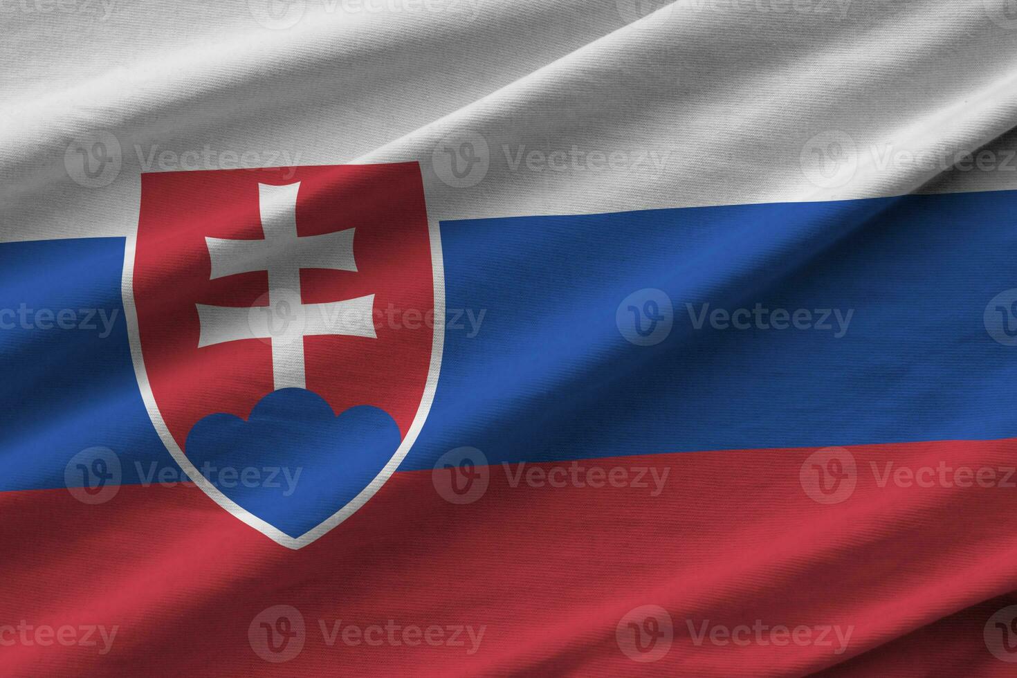 Slovakia flag with big folds waving close up under the studio light indoors. The official symbols and colors in banner photo