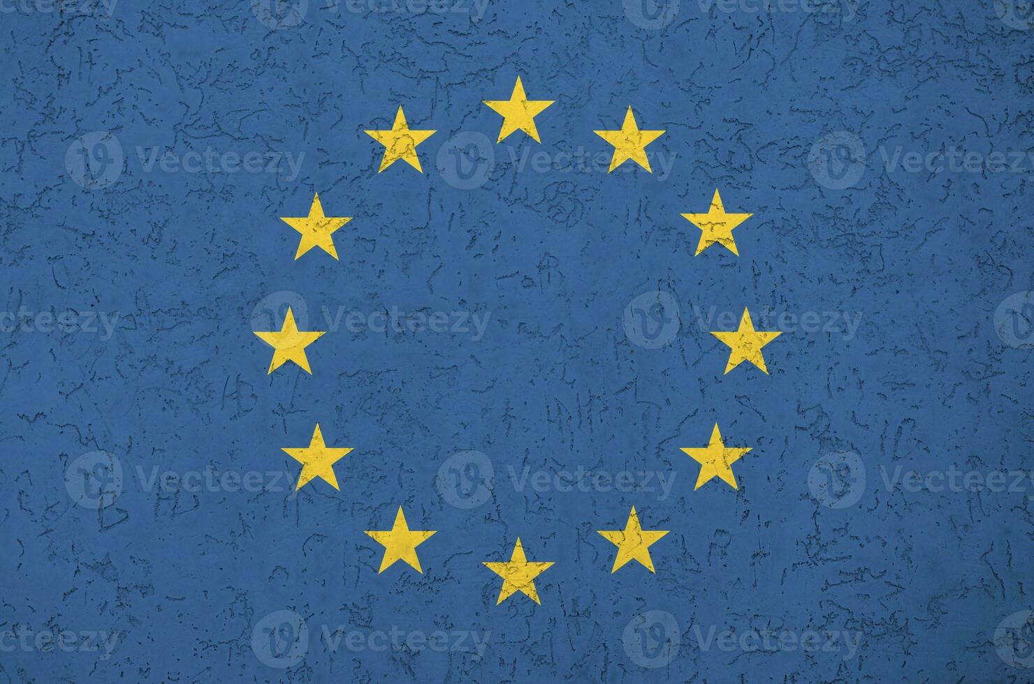 European union flag depicted in bright paint colors on old relief plastering wall. Textured banner on rough background photo