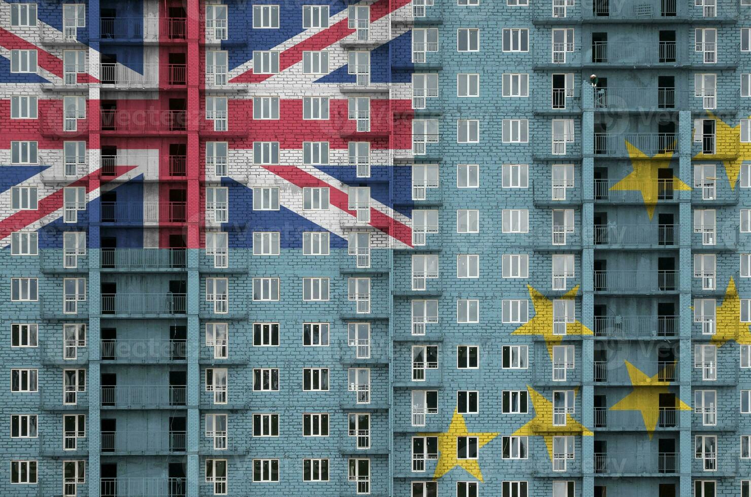 Tuvalu flag depicted in paint colors on multi-storey residental building under construction. Textured banner on brick wall background photo